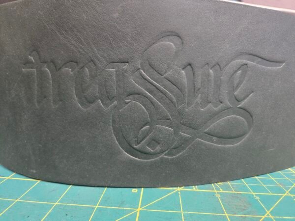 Close-up of the dark green leather Owned Riding Belt “Treasure Belt” showing the embossed word “Treasure.”