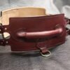 Burgundy English Bridle leather Owned Riding Belt with raised control handle, Royal Star sigil, solid brass hardware, dual side straps, and light leather lining visible inside.