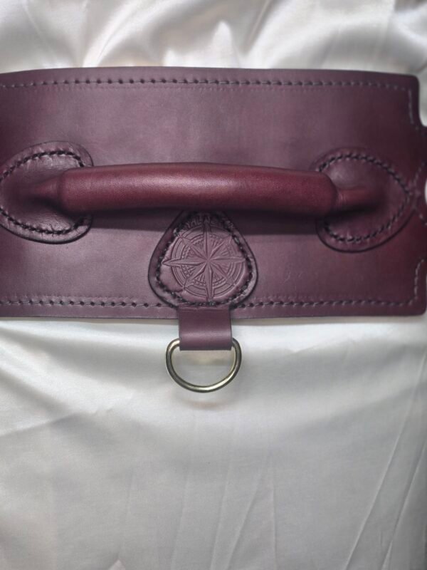 Close-up of the Burgundy English Bridle leather Owned Riding Belt showing the raised control handle, embossed Royal Star sigil, and solid brass D-ring.