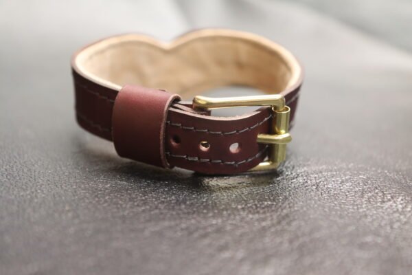 Drop Tip Sigil Collar Burgundy 5 Rear closure detail of the Burgundy English Bridle Drop Tip Sigil Collar, showing the solid brass buckle, adjustment holes, keeper loop, and natural lambskin lining.