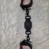 Owned Riding Cuffs - Tethered 2 Black English Bridle leather Owned Riding Wrist Cuffs with red deersplit lining, connected by a matching leather tether with black swivel snap hardware, shown laid out lengthwise.