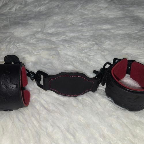 Pair of leather wrist cuffs connected by a matching tether.
