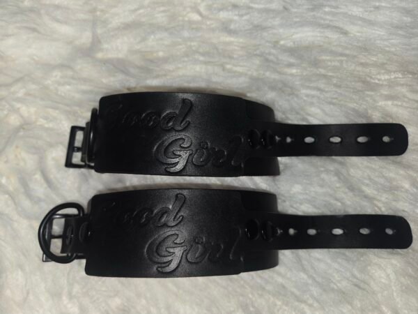Owned Riding Cuffs - Good Girl Embossed Pair of black English Bridle leather Owned Riding Wrist Cuffs with black locking-tongue buckle hardware, embossed “Good Girl,” and pre-curved construction shaped to fit the wrist.