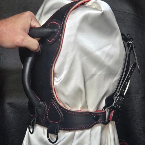 Black Owned Riding Harness on a mannequin with a hand gripping the integrated rear control handle.