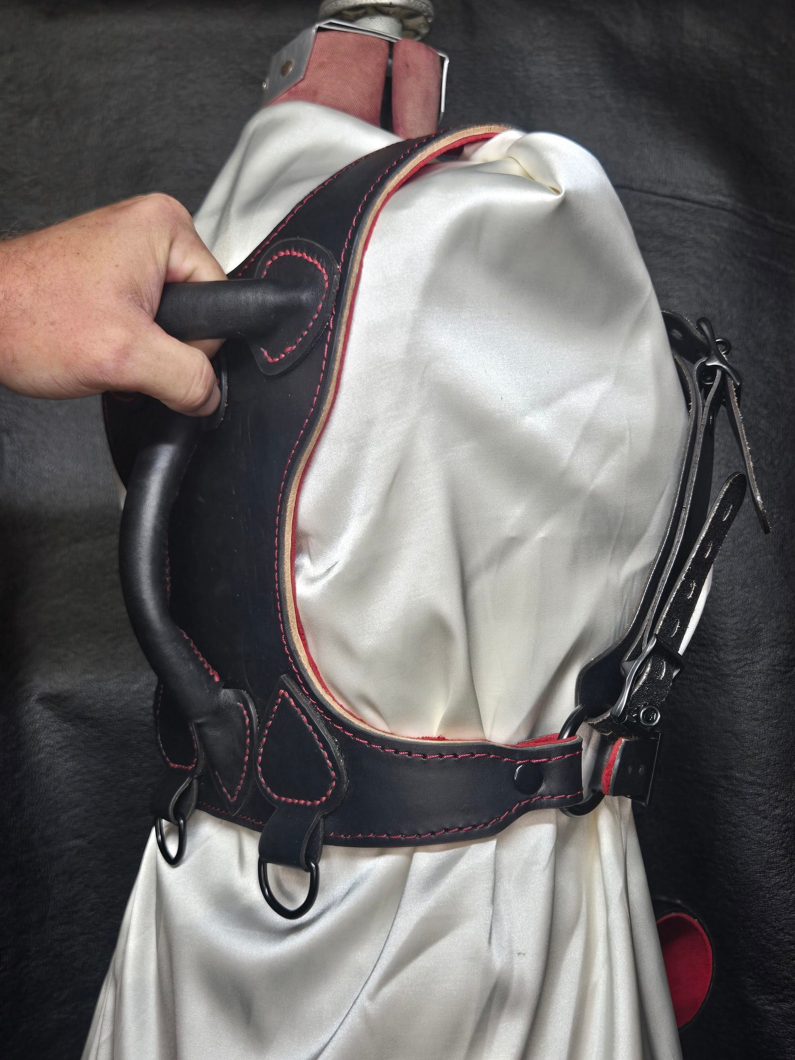 Harness v2.3 - on Mannequin Black - Hand on 1 Black Owned Riding Harness on a mannequin with a hand gripping the integrated rear control handle.