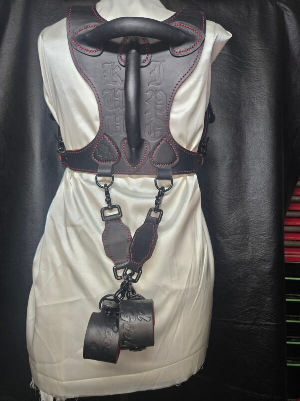 Harness v2.3 - on Mannequin Black - w-Cuffs Black leather Owned Riding BDSM Harness with red stitching, horizontal and vertical handles, two D-ring attachment points, custom embossing, attached tethers, and Owned Riding Cuffs.