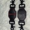 Tethers Pair of black English Bridle leather tethers with red stitching and black swivel snap hardware, shown laid flat on a white fur background.